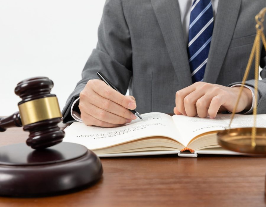 closeup-shot-person-writing-book-with-gavel-table-min